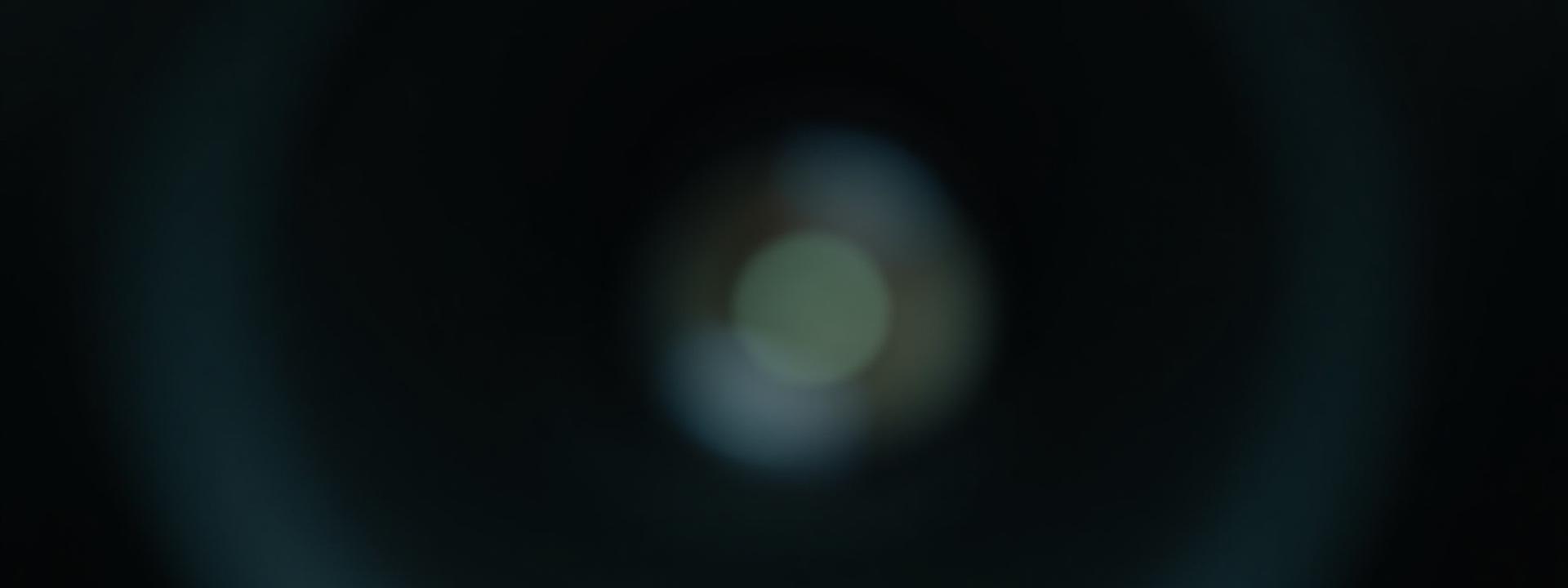 A finely detailed macro shot of a camera lens aperture, slightly blurred, evoking depth and focus.